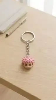 Pink-haired character keychain on a desk